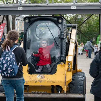 Kid in excavator with parents watching