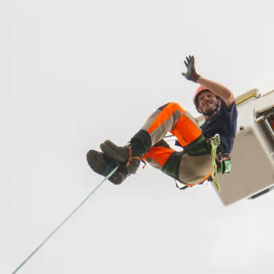 Forestry employee harness and climbing demonstration waiving to attendees