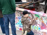 Boy kneeling to paint an outdoor structure