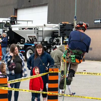 Forestry employee demostrating harness while kids look on