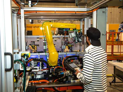 A man working on a robotic machine at a manufacturing facility.