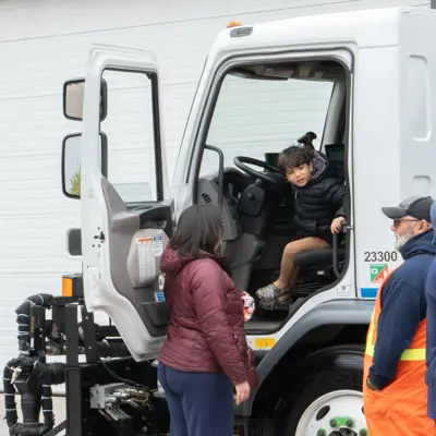 Kid sitting in truck with parents looking on