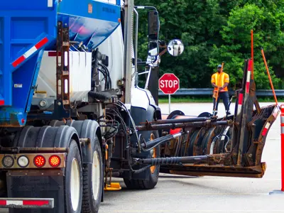 A large track stops in front of a stop sign while a staff member stands in the distance.